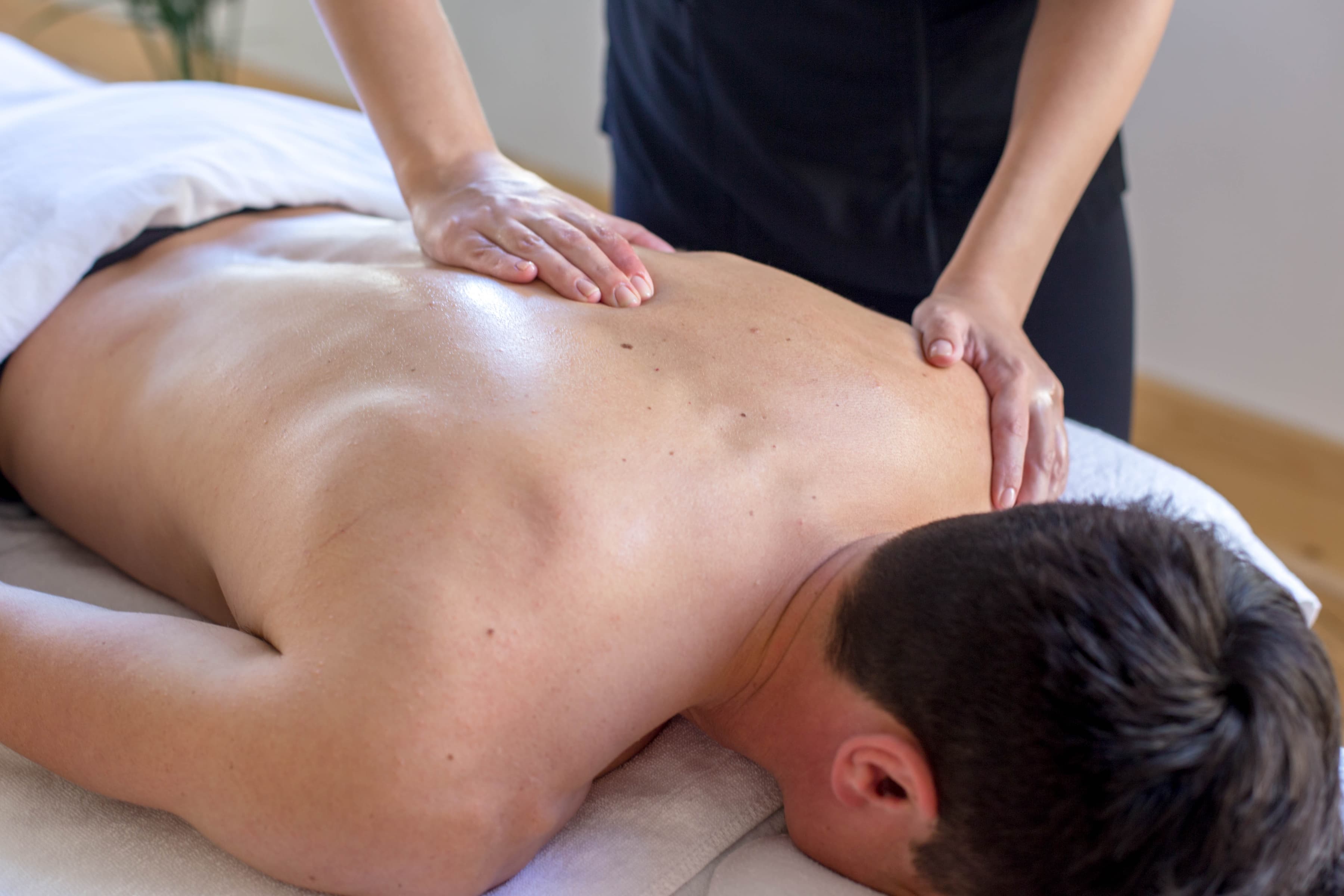 An estheticians hands on a man's back, performing a massage movement